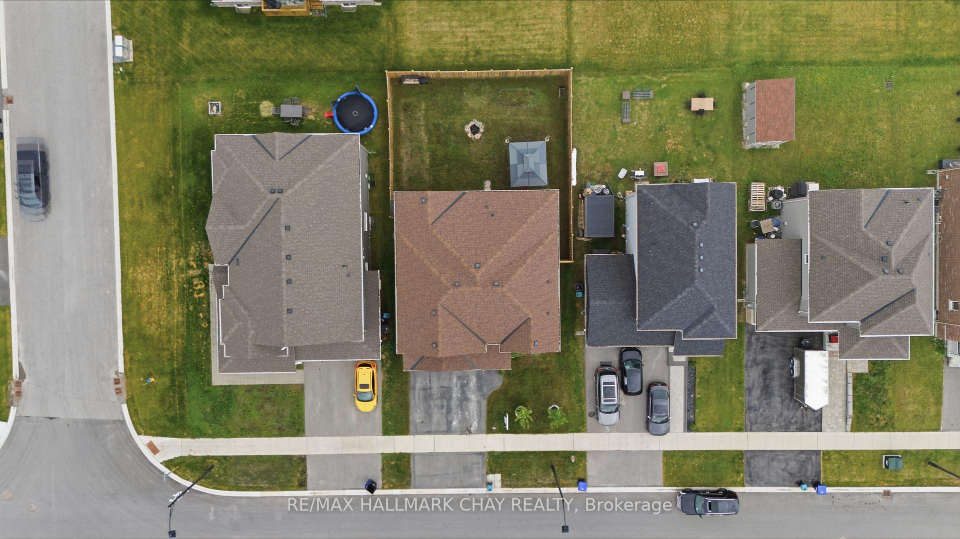 Aerial view of a home with a fenced backyard, fire pit, and neighboring houses.