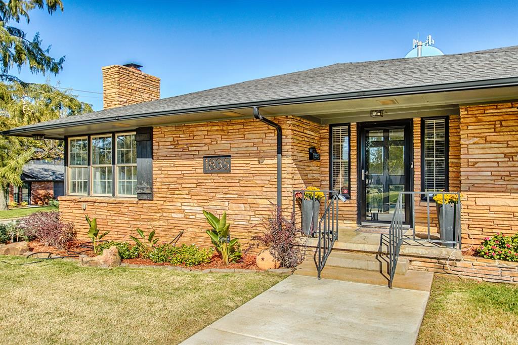 Stone-front single-story home with a covered entry, front walkway, and landscaped yard.