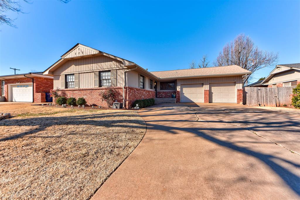 Single-story brick-and-tan house with two garage doors and a wide curved driveway.