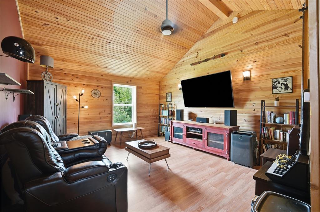 Wood-paneled living room with a vaulted ceiling, leather recliners, and wall-mounted television.
