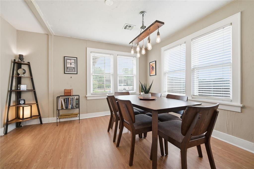 Dining room with a dark wood table, upholstered chairs, and three large windows.