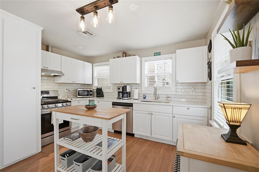 Bright white kitchen with stainless steel appliances, subway tile backsplash, and a butcher-block island.
