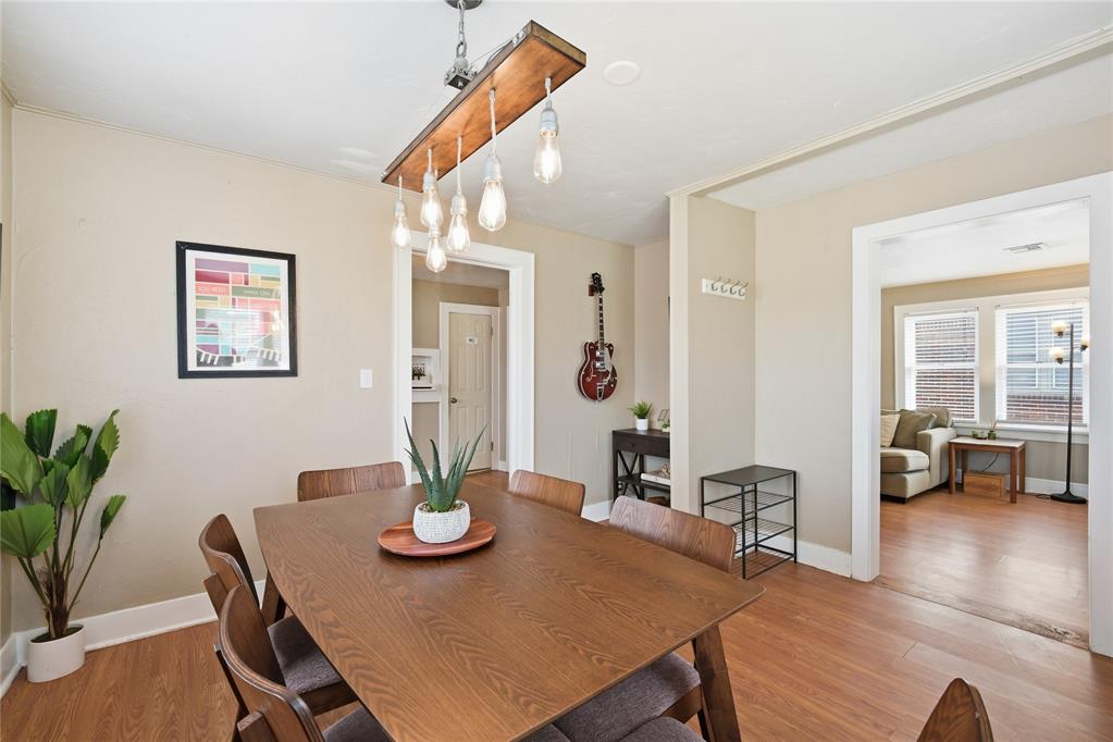 Dining room with a large wooden table, pendant lights, and an open doorway to the living room.