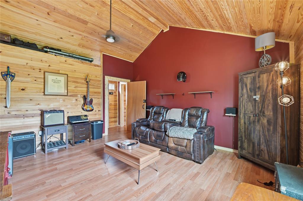 Living room with a vaulted wood ceiling, red accent wall, leather sofa, and guitars.