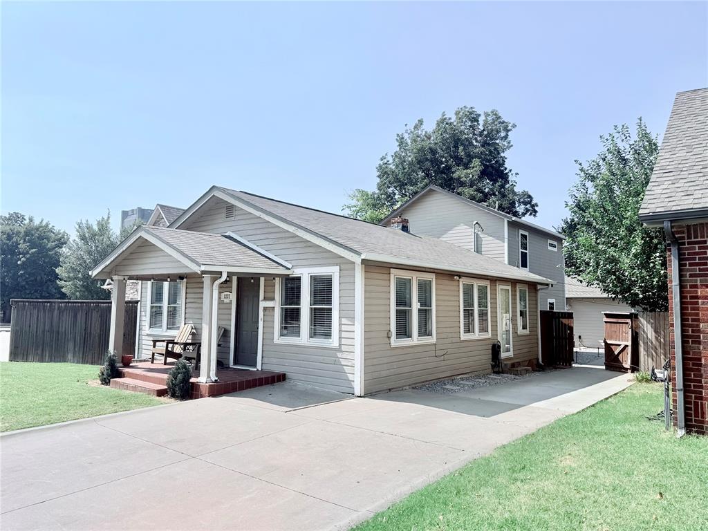 Tan house with a small covered porch, white-trimmed windows, and a wide concrete driveway.