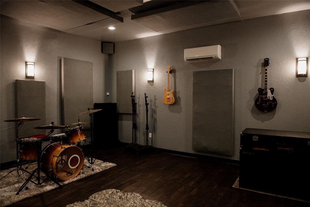 Music room with a drum kit, wall-mounted guitars, and acoustic panels.
