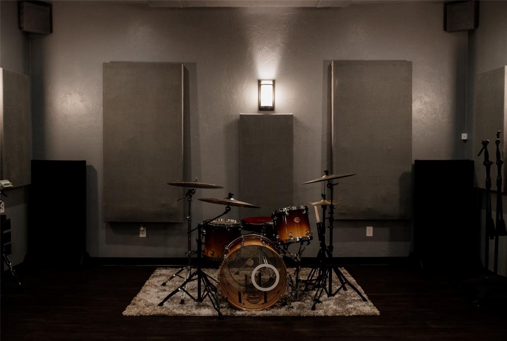 Music room with a drum kit, acoustic wall panels, and speakers.