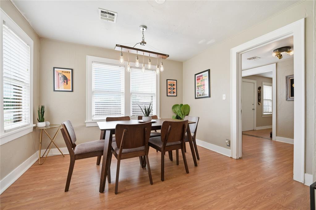 Dining room with a dark wood table, window blinds, and a linear pendant light.