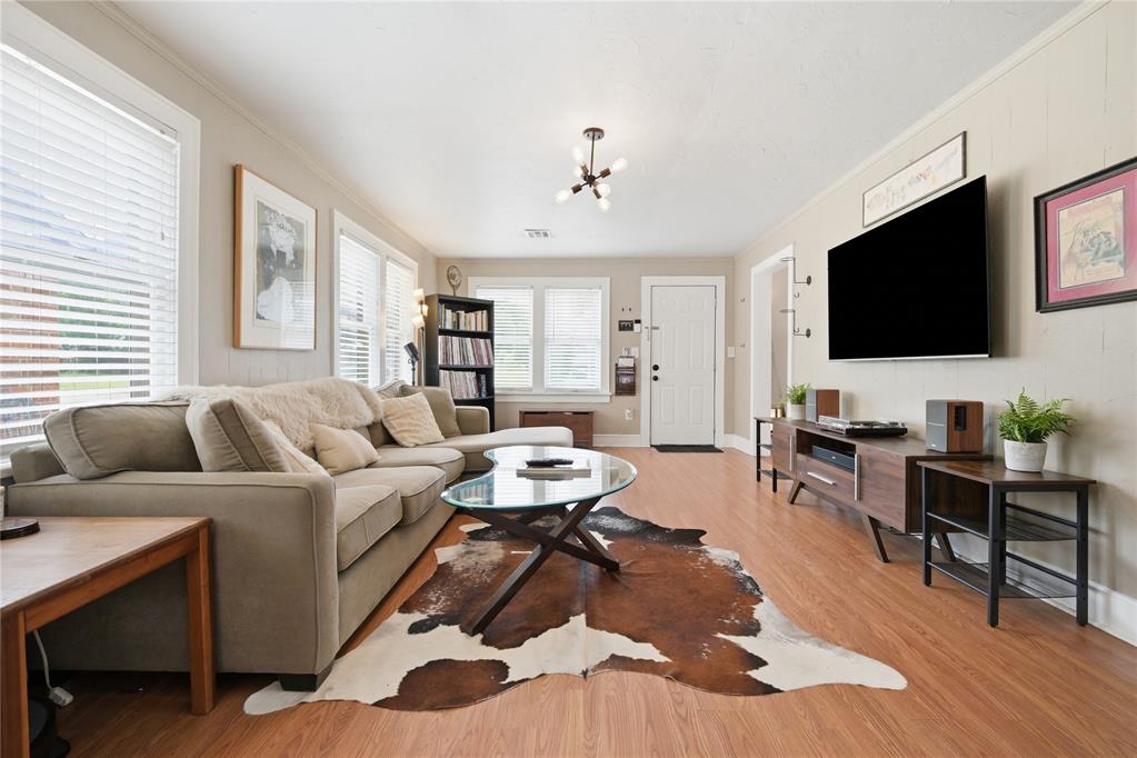 Living room with a beige sectional, cowhide rug, wood floors, and wall-mounted television.