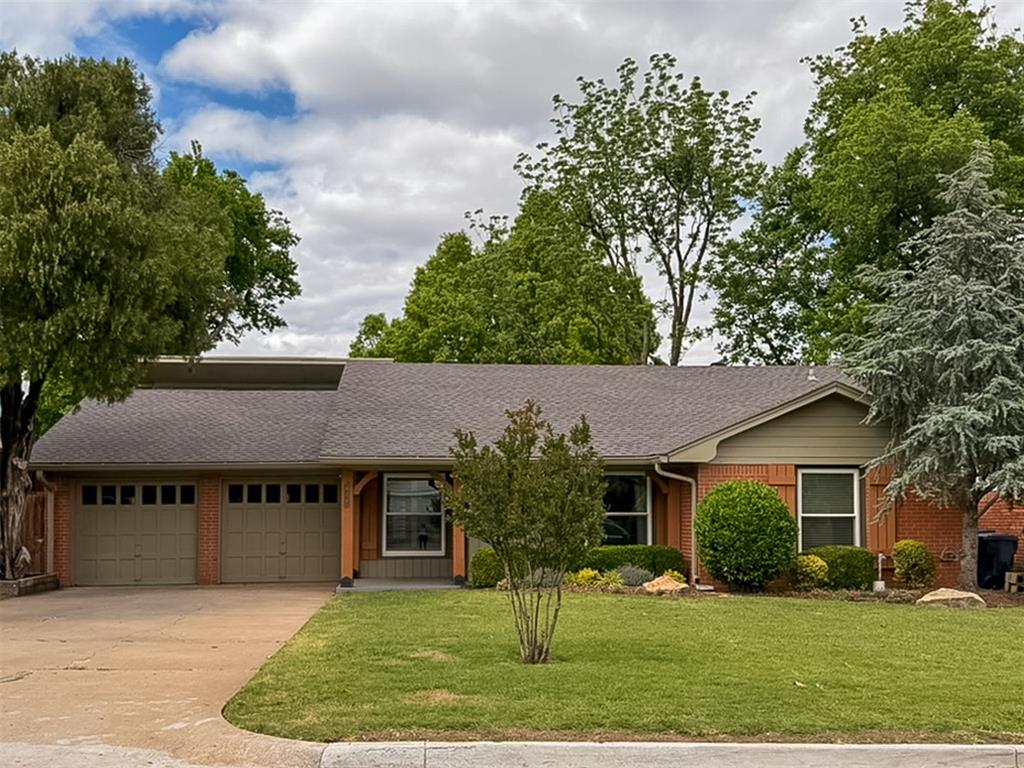 Single-story brick house with a two-car garage, broad lawn, and mature trees.