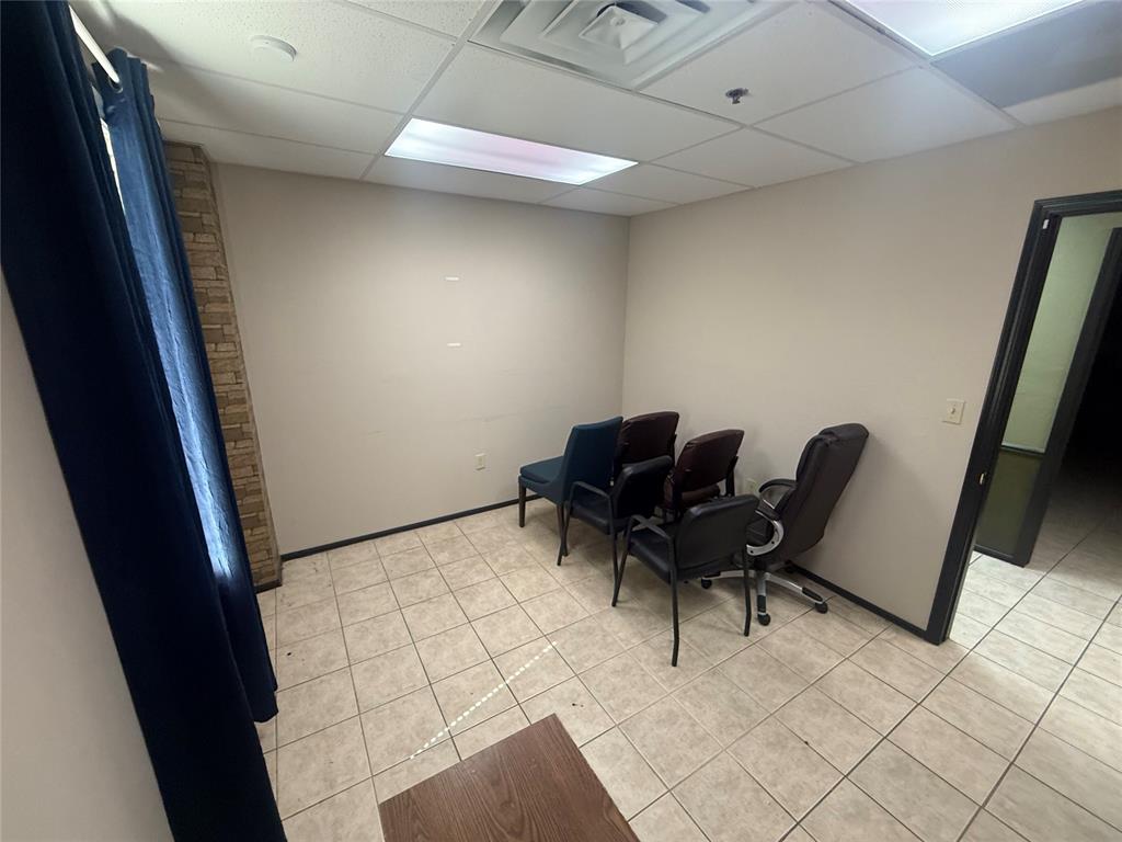 Office waiting area with several chairs, beige tile flooring, and a dark blue curtain.