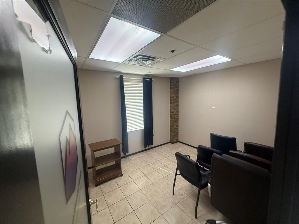 Furnished office meeting room with tiled floors, window blinds, and several chairs.