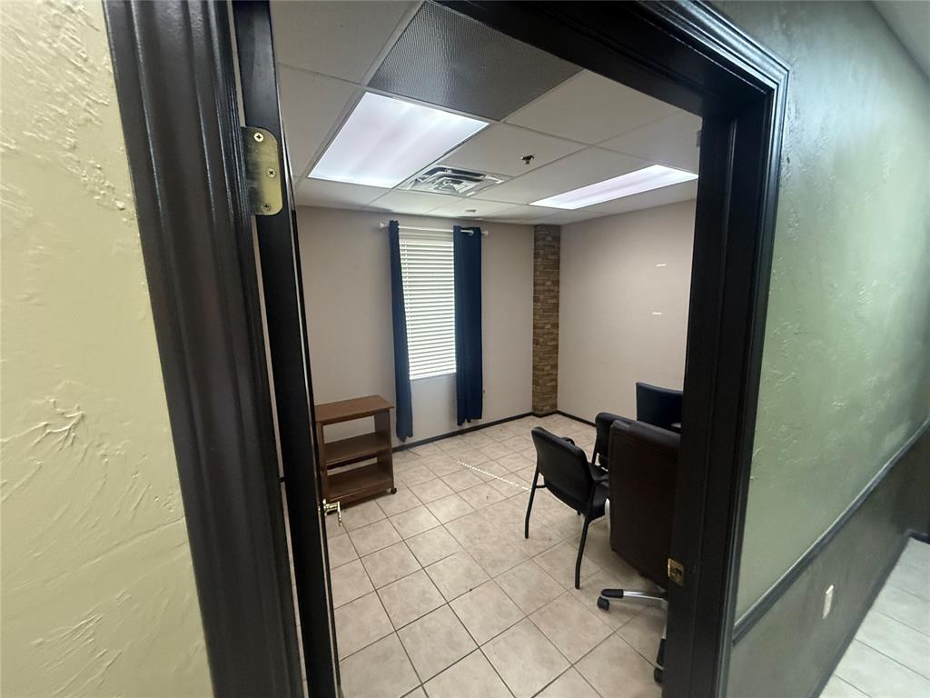 Office with tiled floors, a window with blinds, and chairs around a small table.