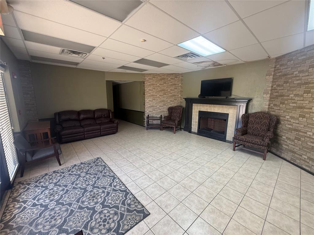 Furnished commercial lounge with leather sofa, tiled floor, and stone fireplace.