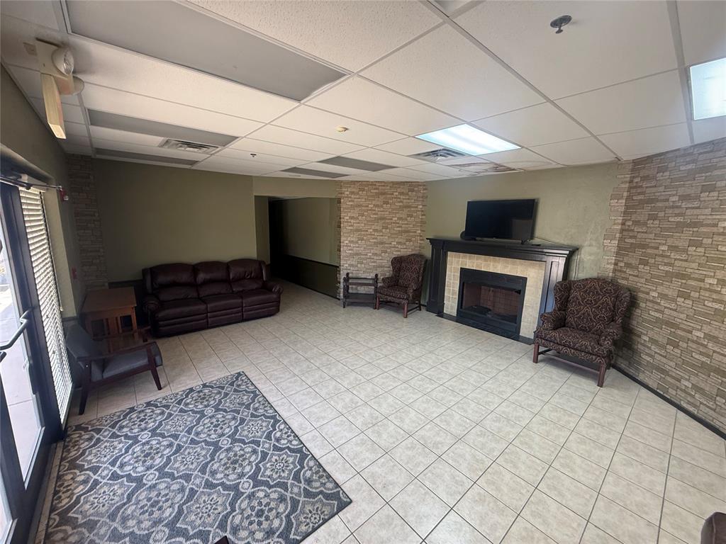 Furnished lounge with a fireplace, leather sofa, patterned armchairs, and stone accent walls.