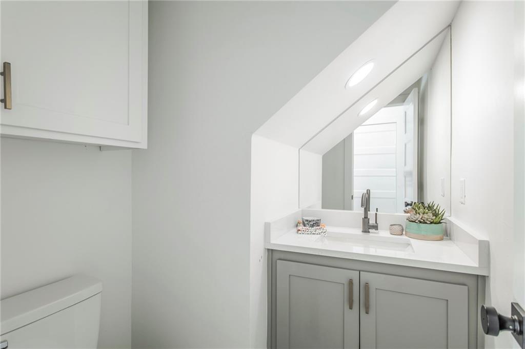 Bathroom vanity with a white countertop, large mirror, and potted succulent.