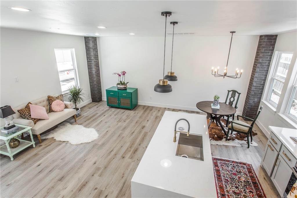Open-plan kitchen and living area with a white island, dining nook, and brick columns.