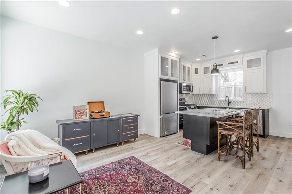 Bright kitchen with a black island, white cabinetry, hexagonal backsplash, and adjacent lounge area.