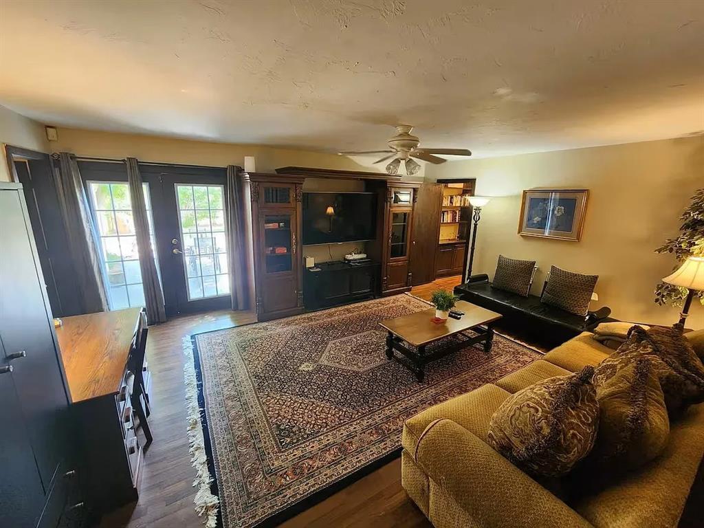 Living room with French doors, a wood entertainment center, patterned rug, and sofas.