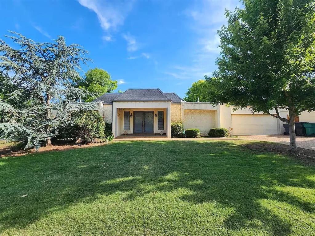Single-story home with a recessed double-door entry, attached garage, and mature shade trees.