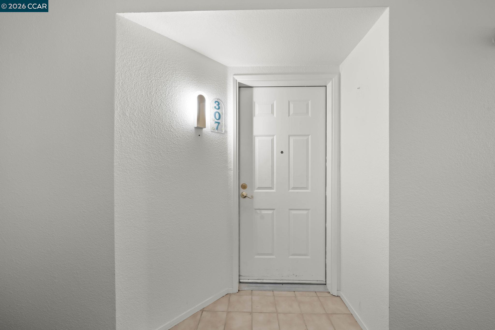 Entry foyer with a white paneled door marked 307 and beige tile flooring.