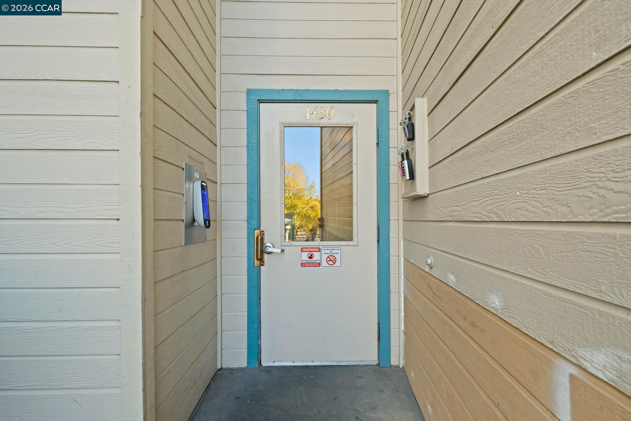 Building entrance with a gray door, turquoise trim, keypad, and lockboxes.