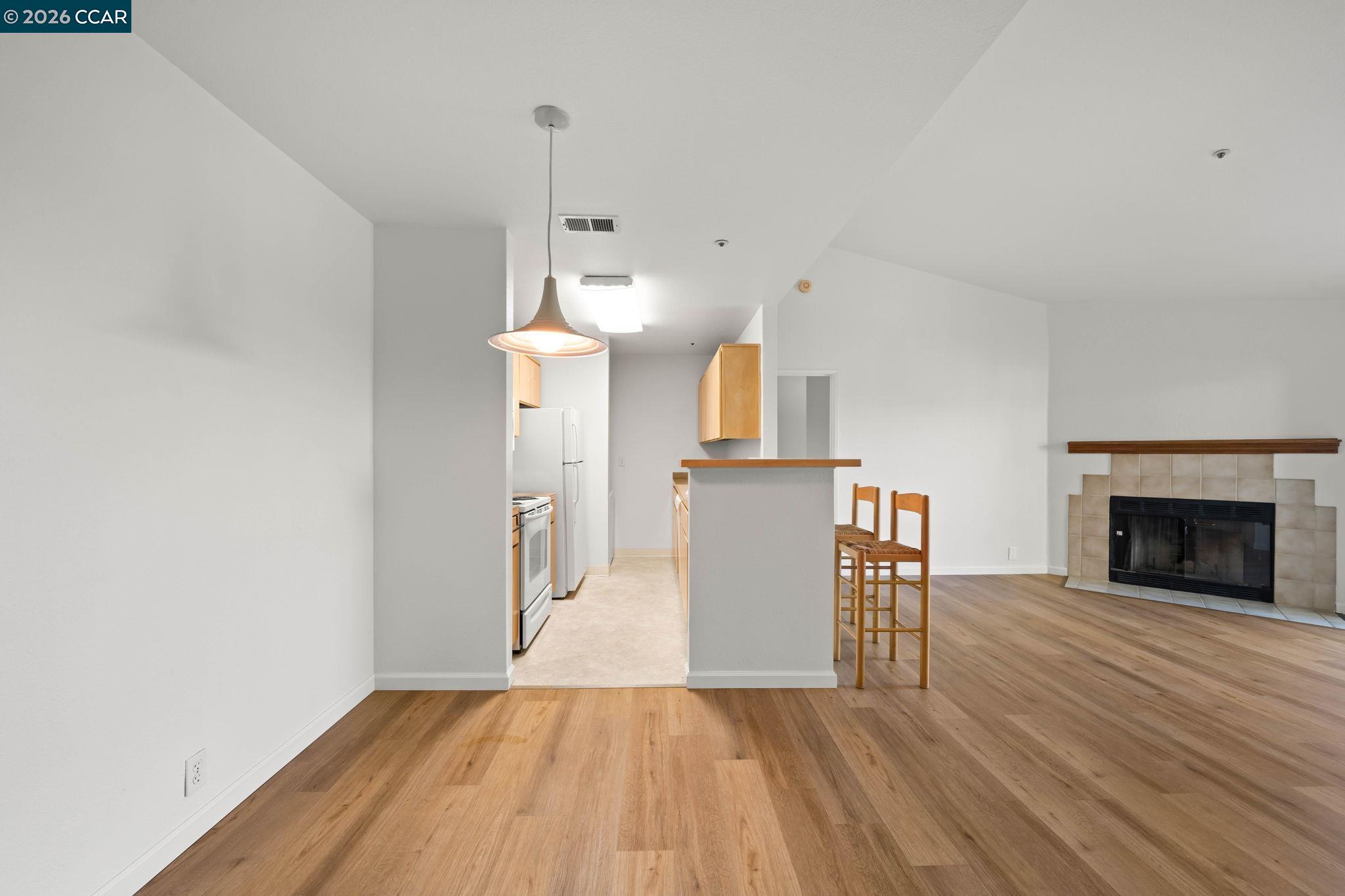 Open-plan condo living area and kitchen with a breakfast bar and tiled fireplace.