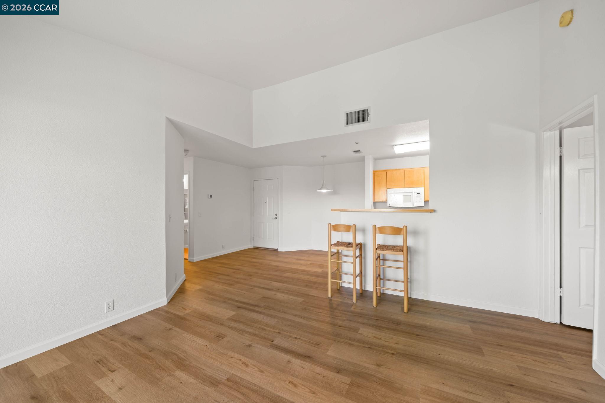 Open dining area with wood-look floors, a breakfast bar, and two wooden stools.