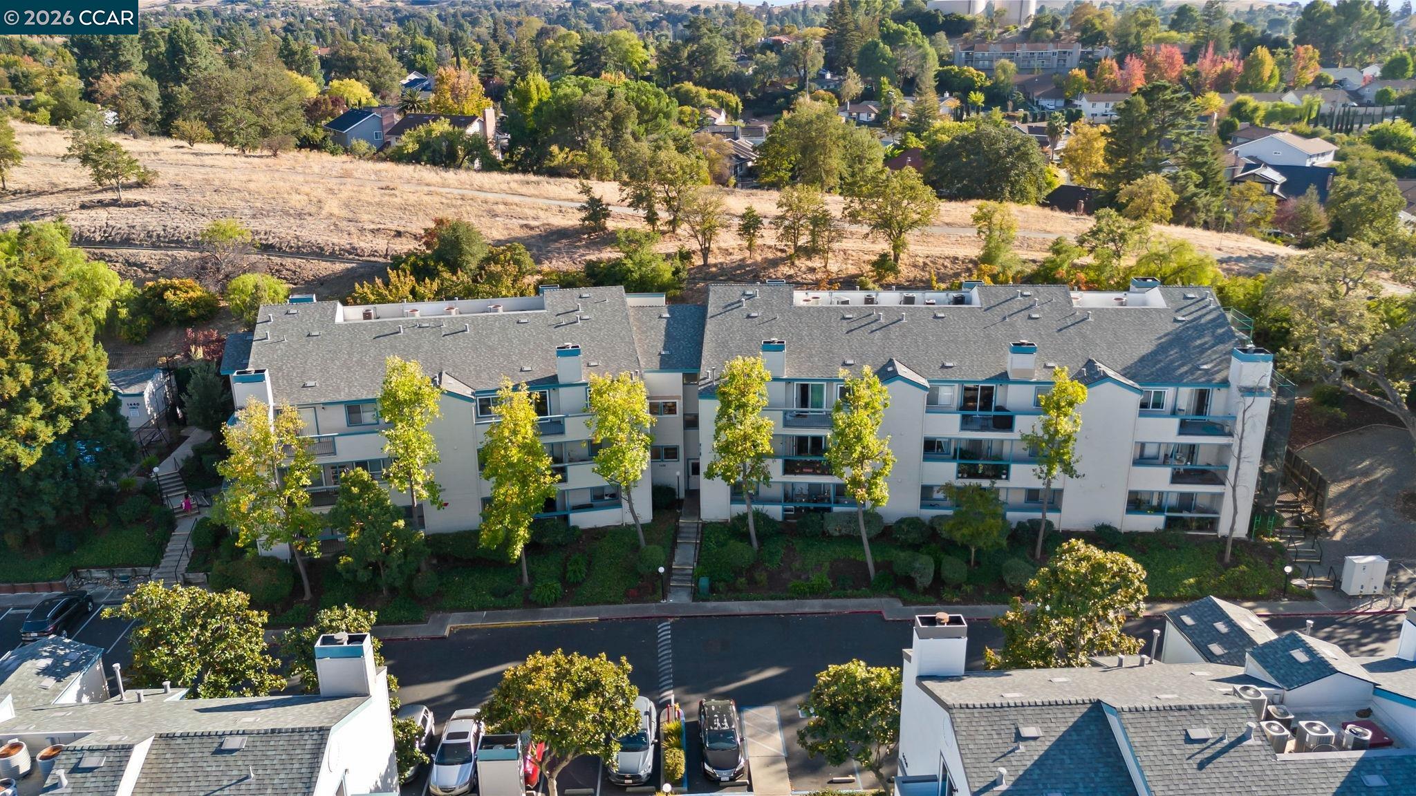 Aerial view of a condominium complex beside a dry hillside and residential neighborhood.