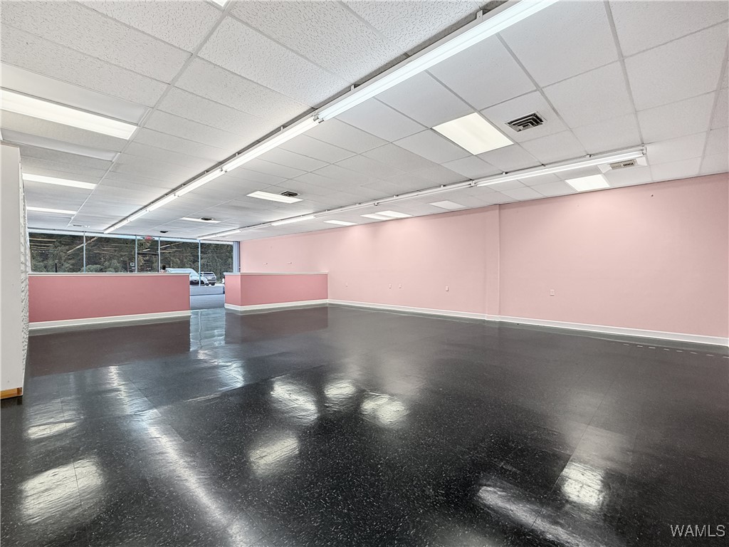 Empty retail suite with pink walls, dark polished flooring, and front windows.