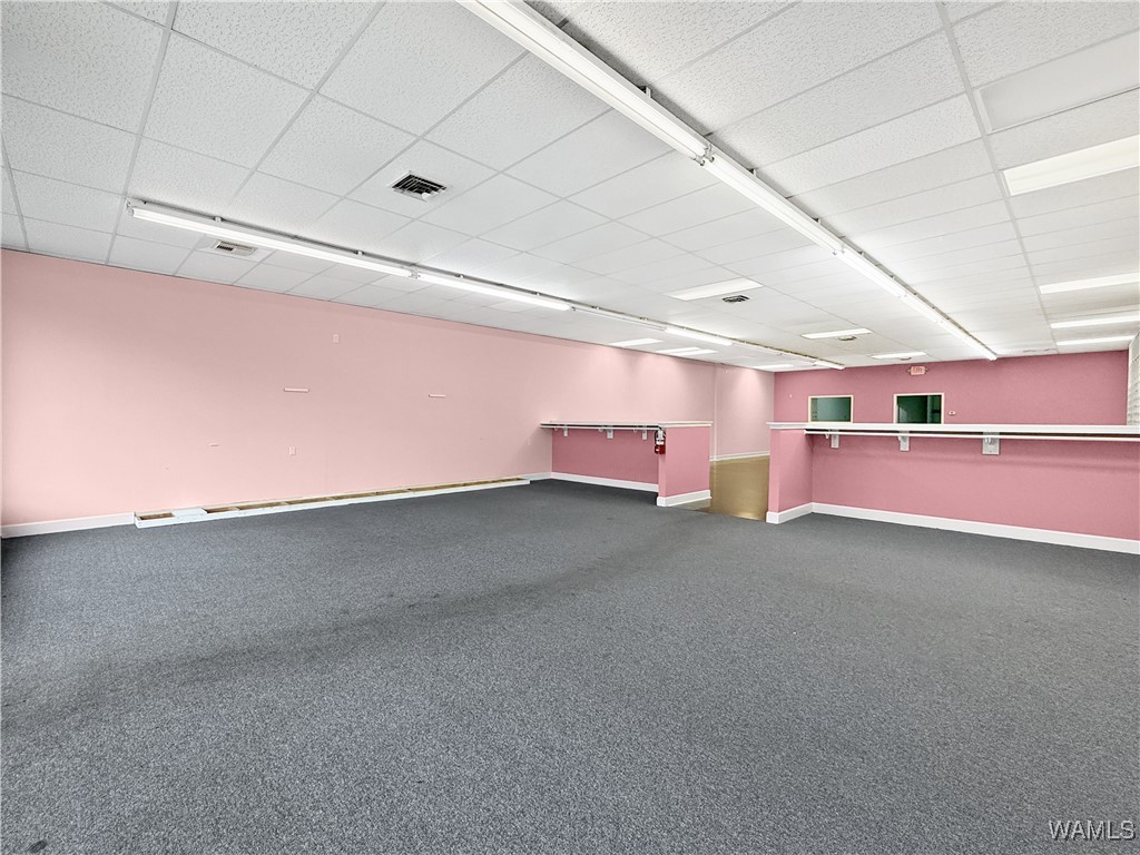 Vacant retail suite with pink walls, gray carpet, and long counters.