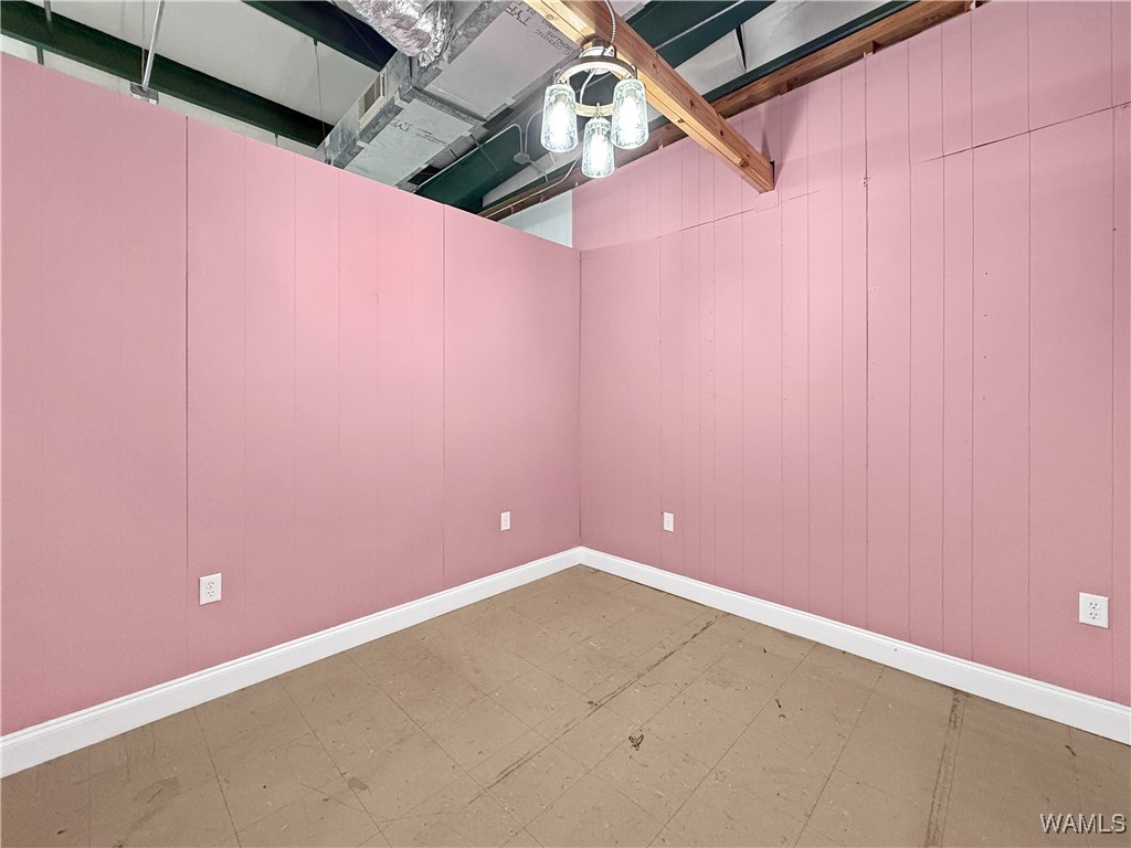Empty retail suite with pink walls, a bare floor, and an exposed ceiling.