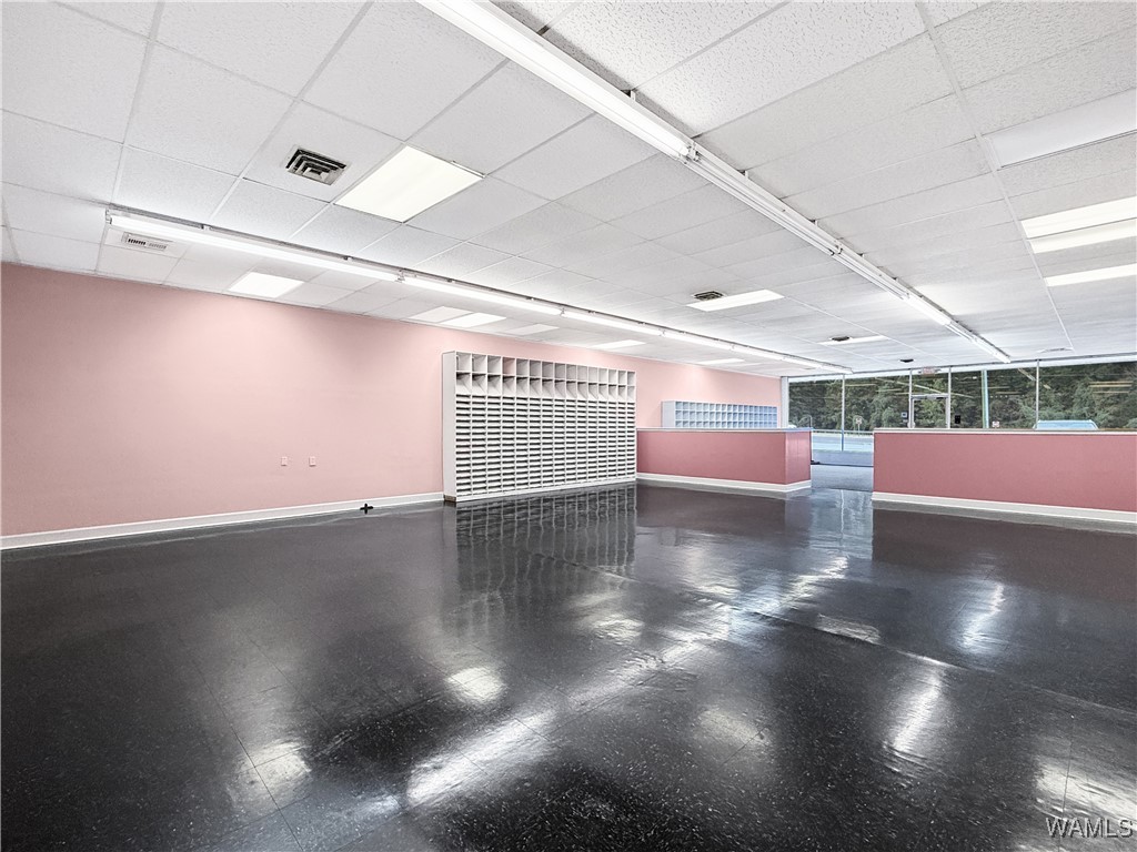 Vacant retail suite with pink walls, built-in cubbies, pink counters, and large windows.