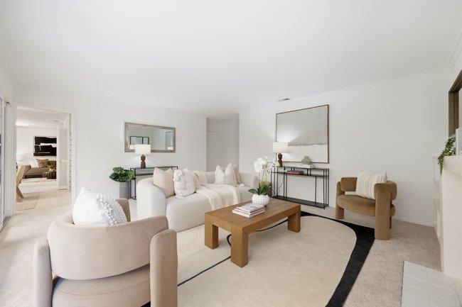 Staged living room with a white sofa, wooden coffee table, and light rug with a dark border.