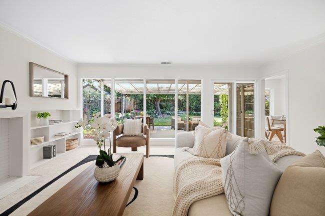 Bright living room with white seating, built-in shelving, and wide garden-facing glass doors.