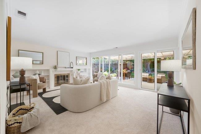 Living room with a fireplace, white sofas, and sliding glass doors opening to a patio.