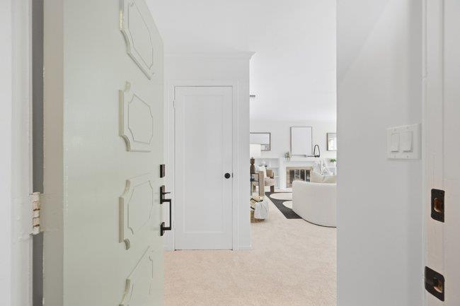 Open front door looking into a bright living area with a curved white sofa and kitchen beyond.