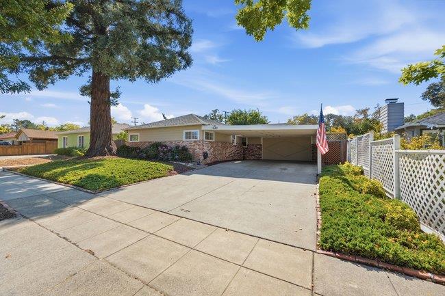 Single-story home with a wide concrete driveway, attached garage, and large front-yard tree.