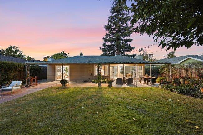 Single-story home and covered patio overlooking a grassy backyard at sunset.