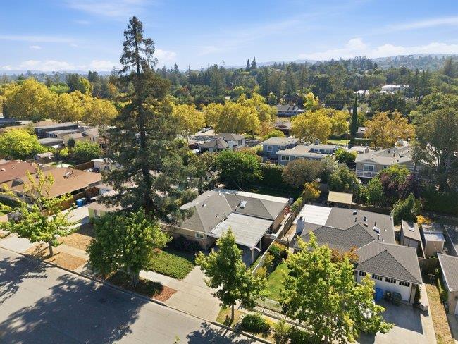 Aerial view of homes among mature trees, with low hills in the distance.
