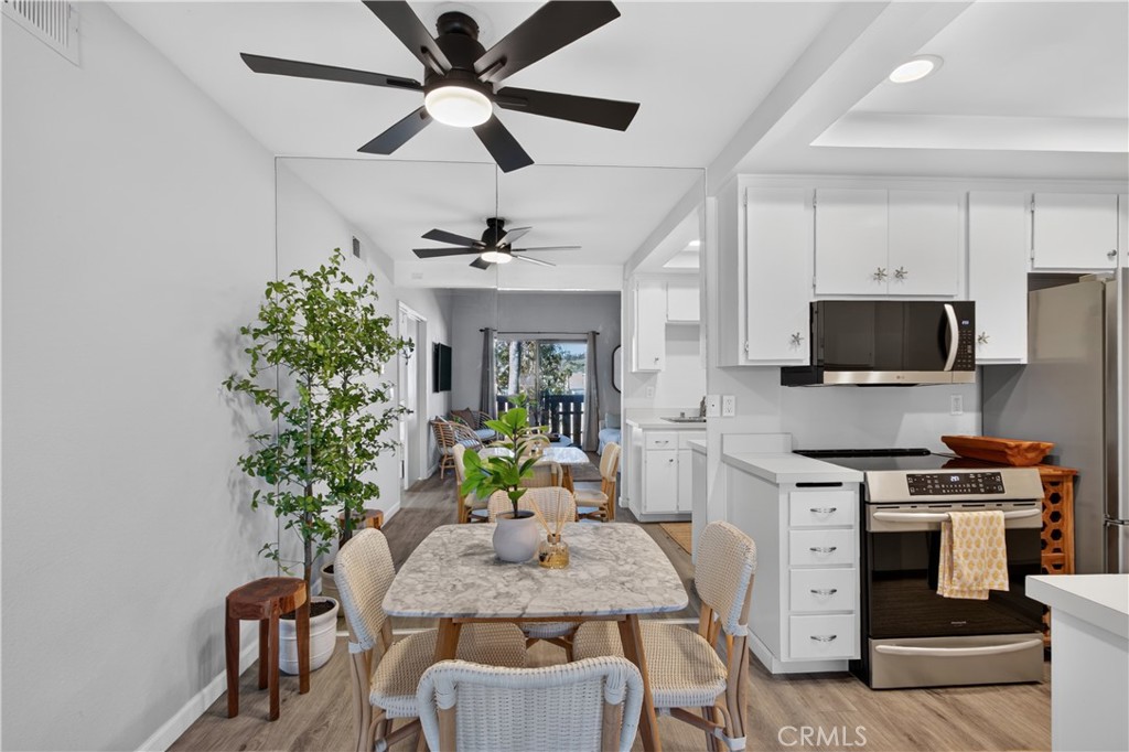 Open-plan kitchen and dining area with white cabinets, stainless steel appliances, and a marble-look table.