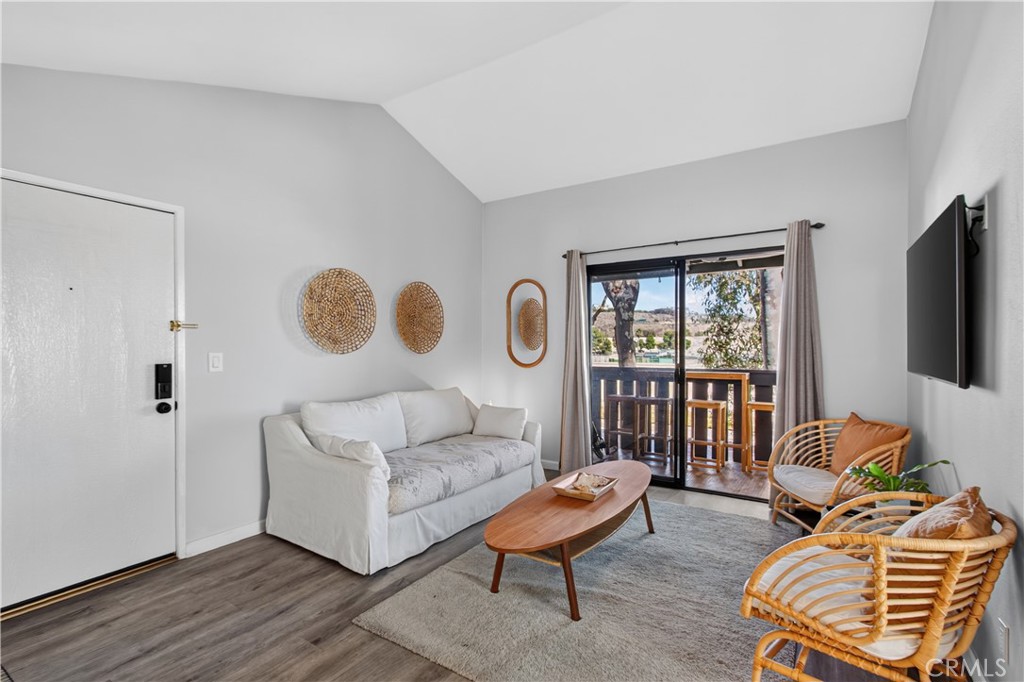 Living room with a white sofa, rattan chairs, and sliding doors opening to a balcony.