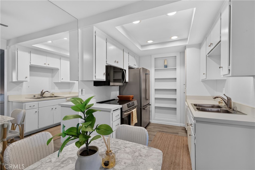 Kitchen with white cabinets, stainless steel appliances, and a dining table with wicker chairs.