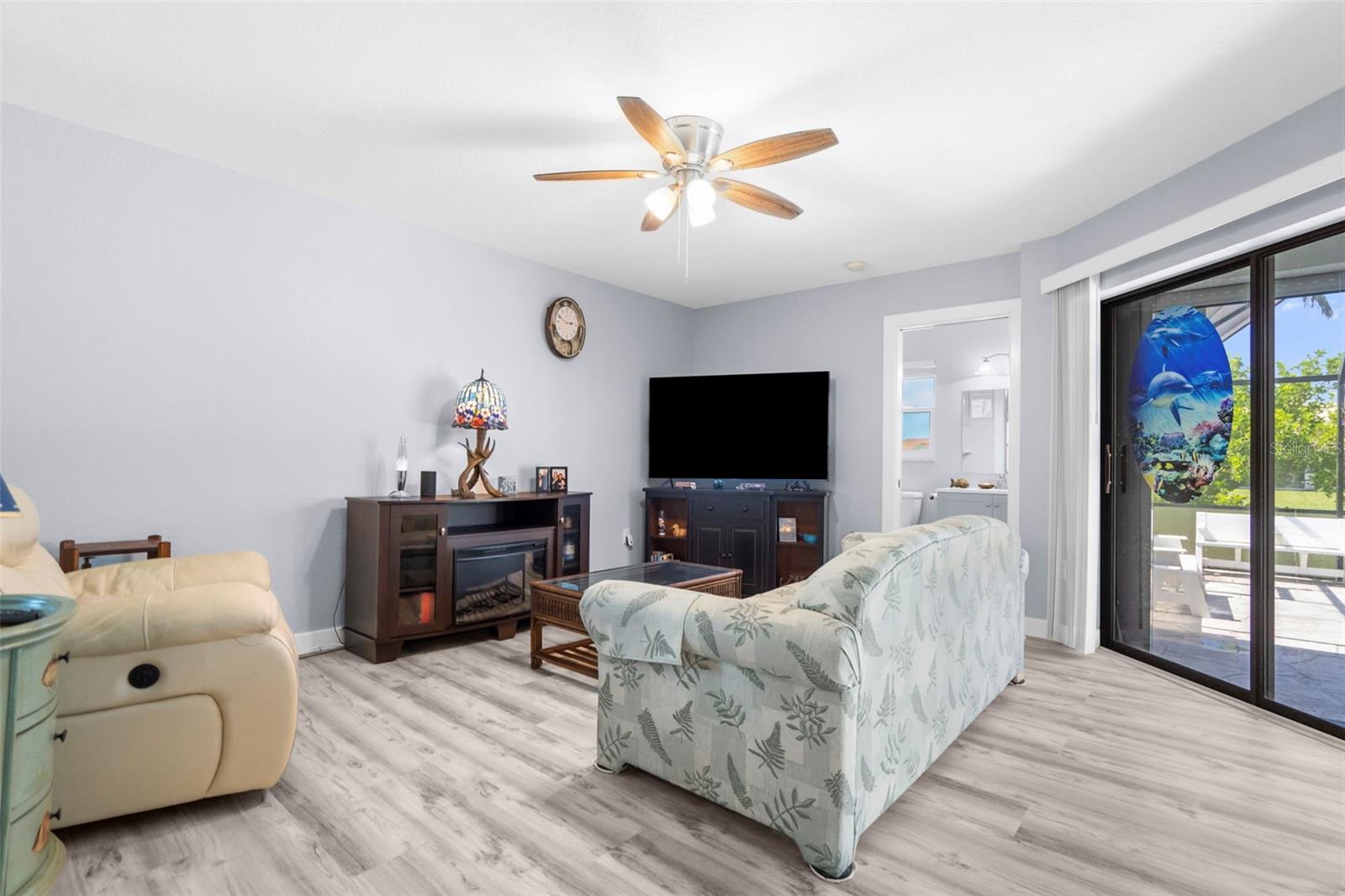 Furnished living room with a ceiling fan, gray flooring, and sliding glass doors to a patio.