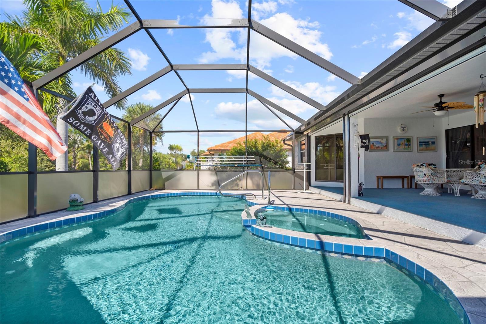 Screened backyard pool with a raised spa and covered patio seating.