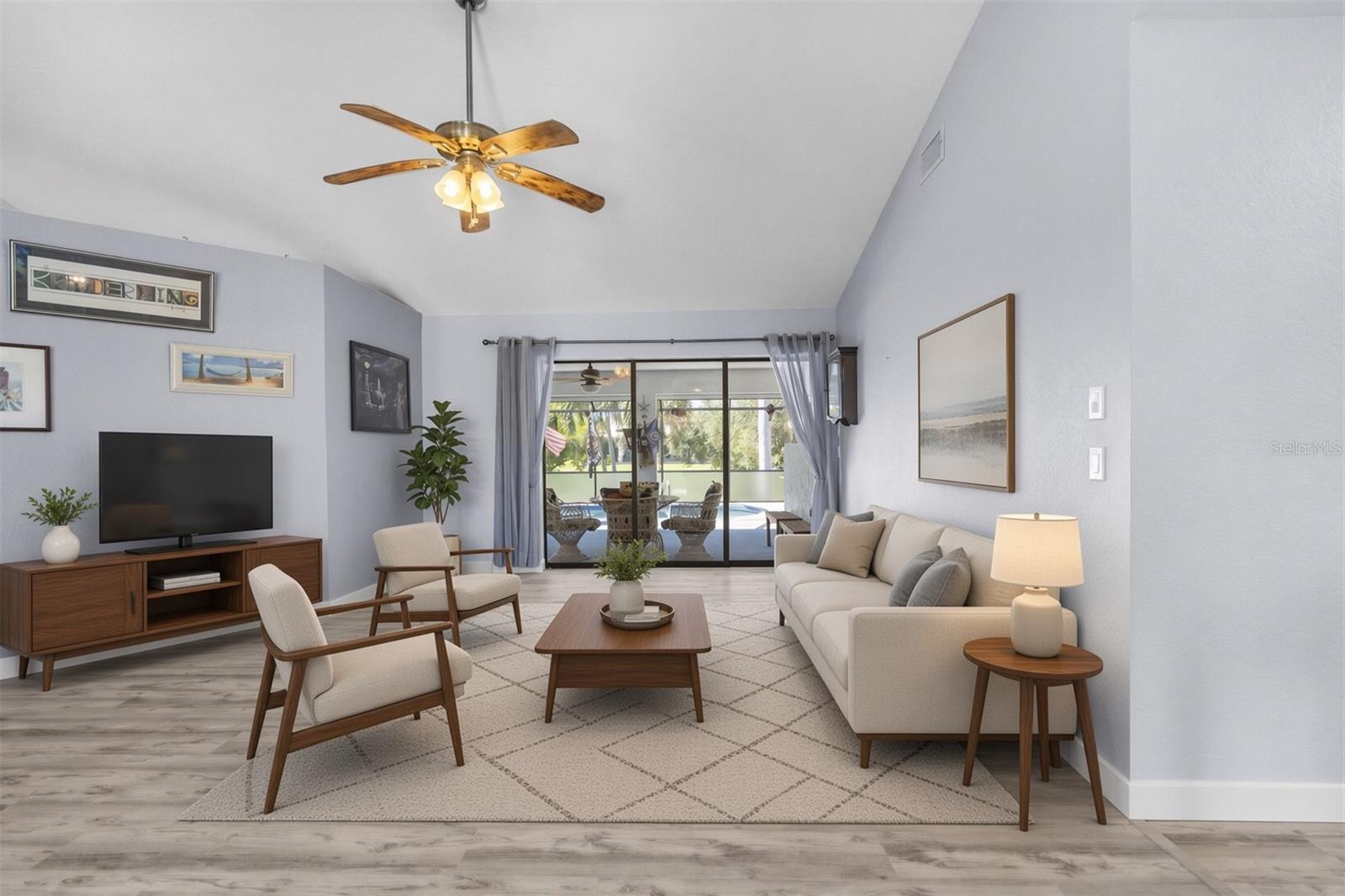 Living room with a vaulted ceiling and sliding doors opening to a covered patio and pool.