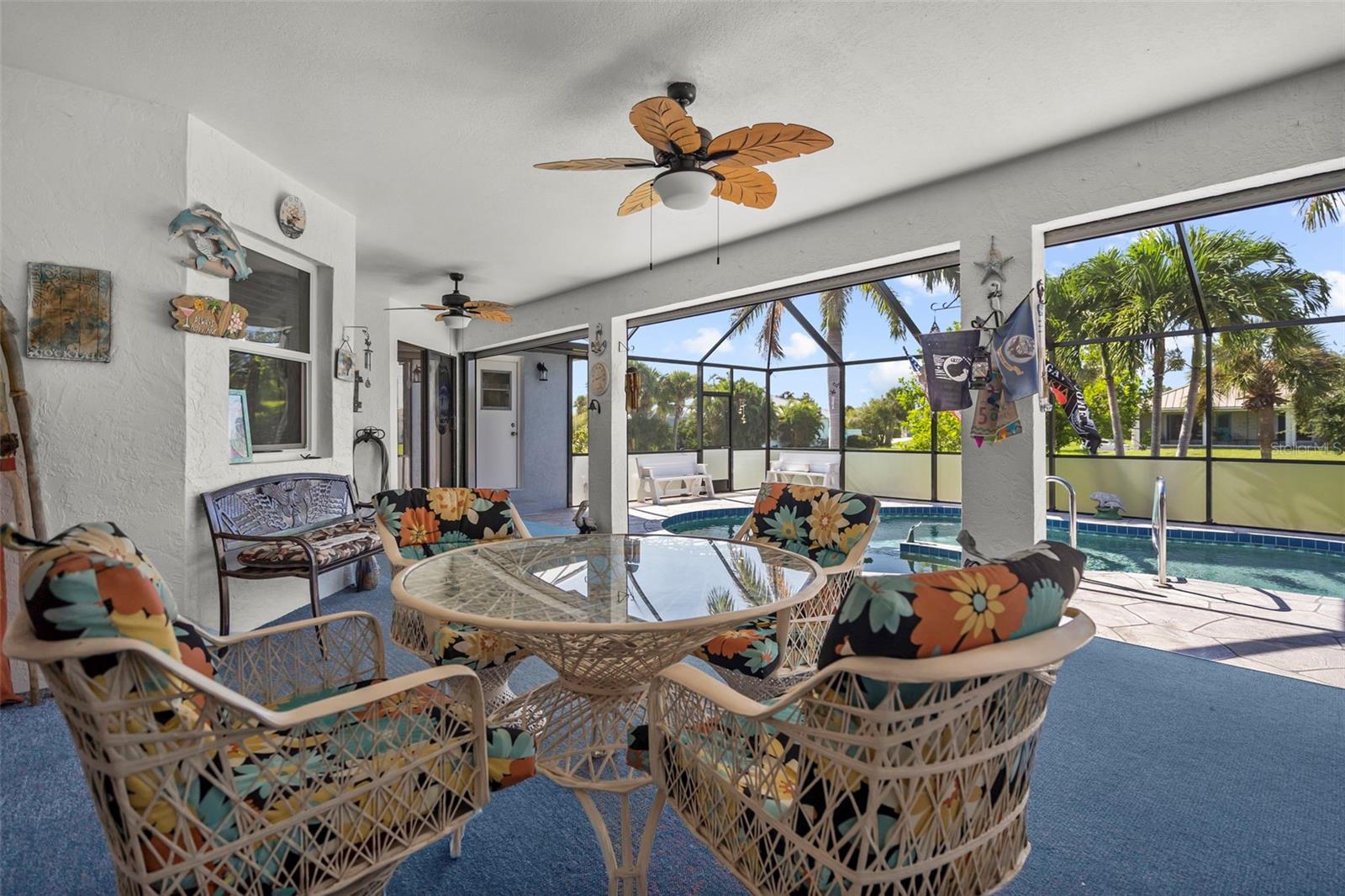 Screened patio with wicker seating overlooking a pool and palm trees.