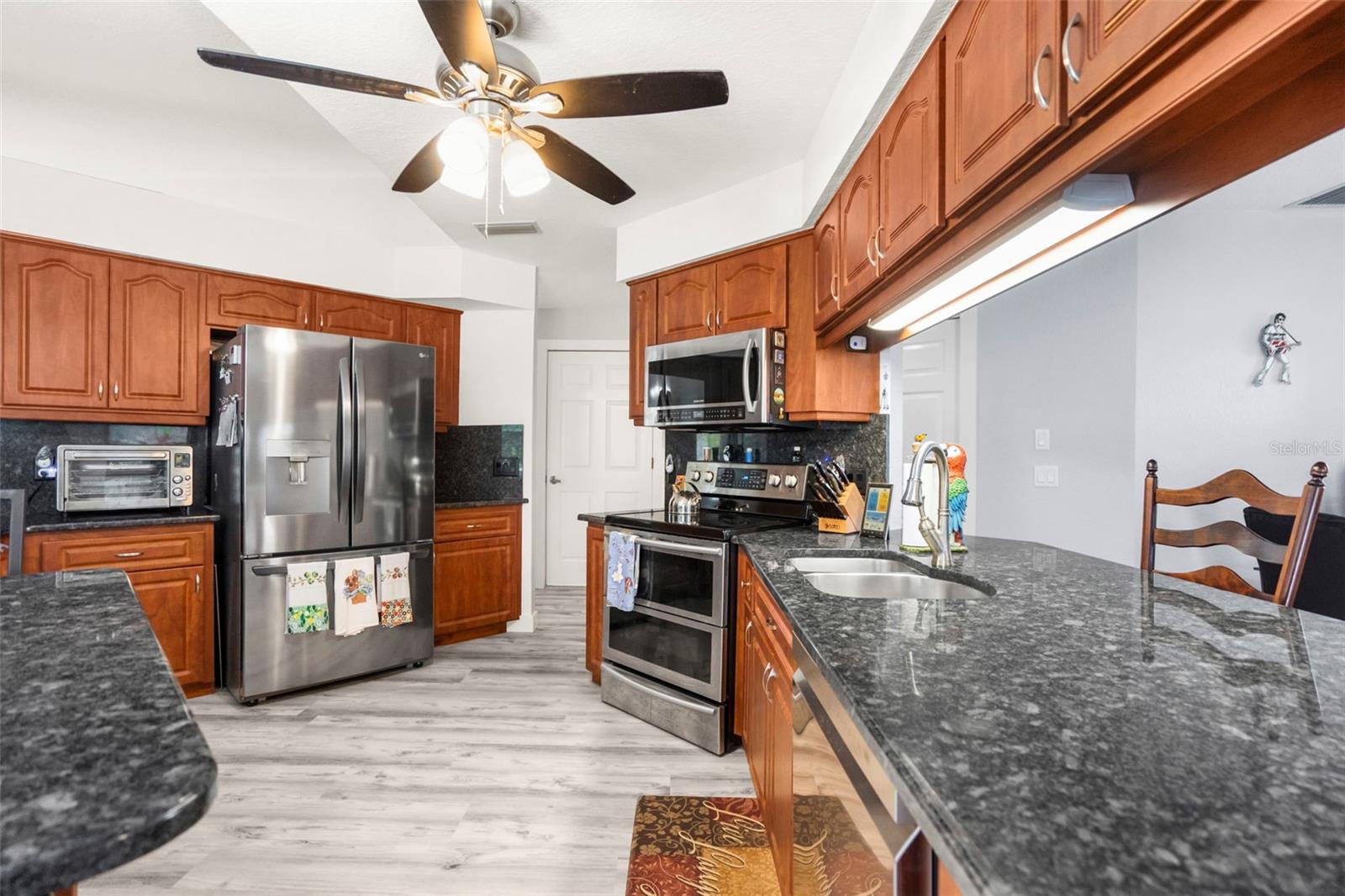 Kitchen with reddish-brown cabinets, dark granite counters, and stainless steel appliances.