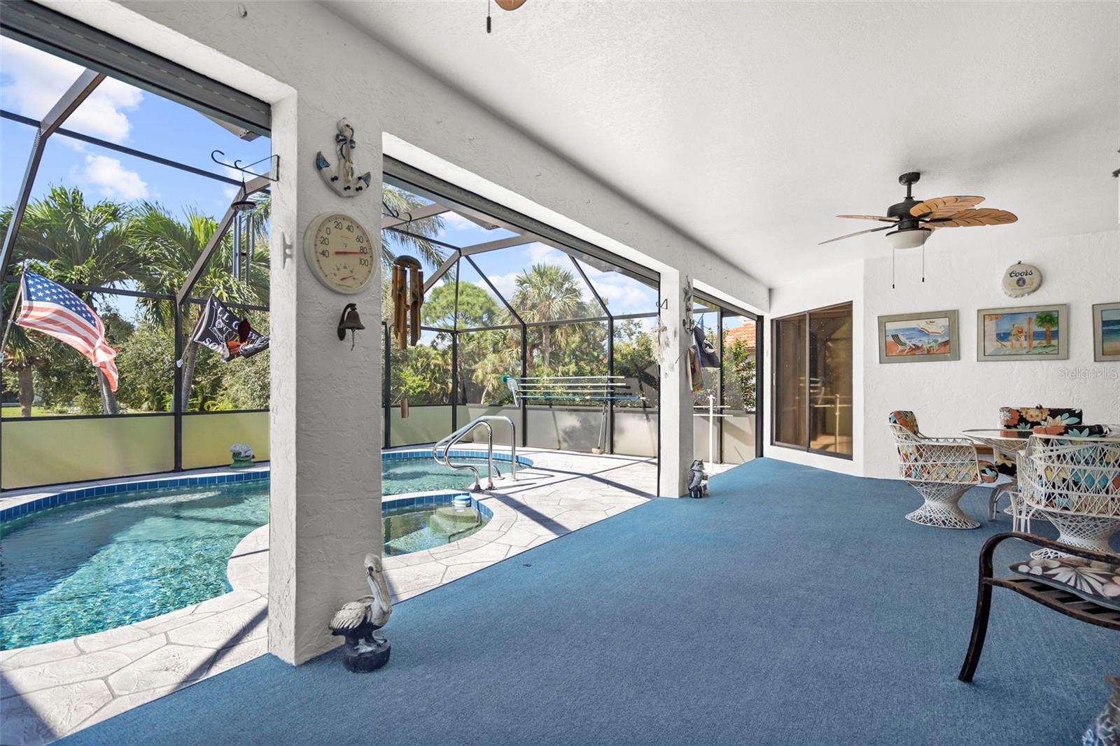 Screened lanai with a pool, blue carpet, and patio seating.