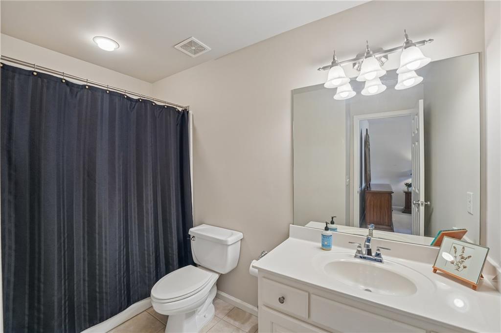 Bathroom with a white vanity, large mirror, toilet, and dark shower curtain.